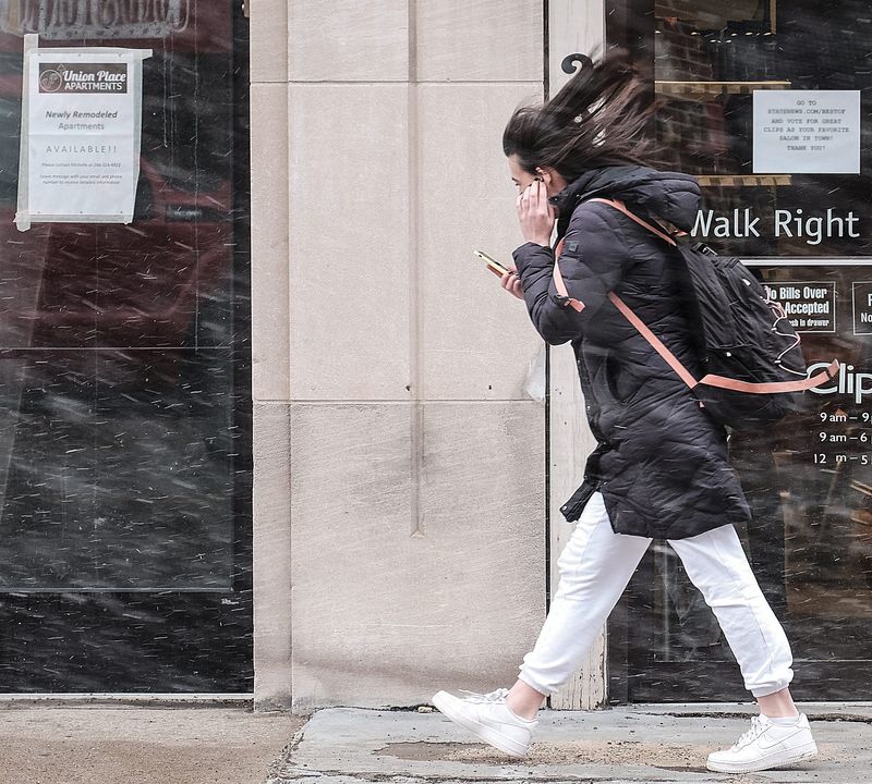 Strong winds blow the snow and this womans hair around in East Lansing Sunday, Feb. 24, 2019. The area is under a High Wind Warning with gusts reaching as high as 65 mph.