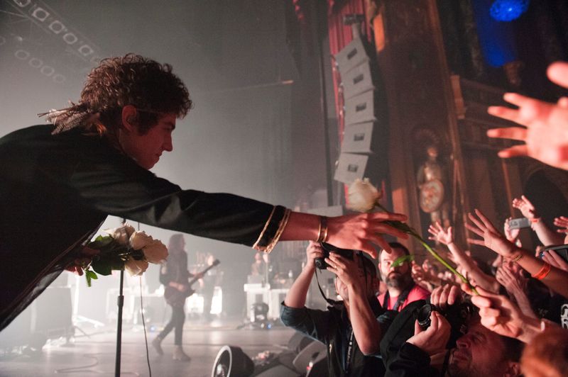 Greta Van Fleet lead singer Josh Kiszka hands out a bouquet of white roses to fans in the front row before the show.