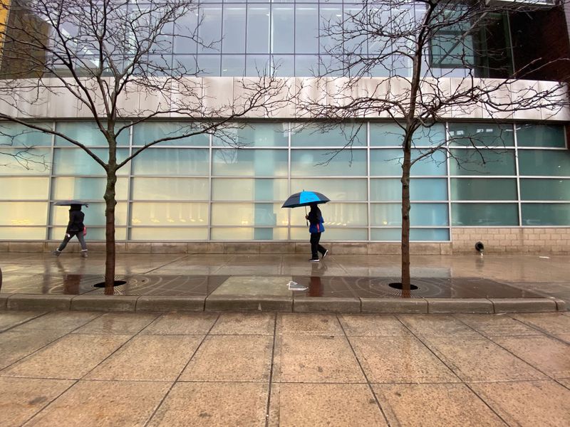 With umbrellas in hand, people make their way down Broadway Street in front of the Boll Family Y in downtown Detroit on Saturday, Jan. 11, 2020.