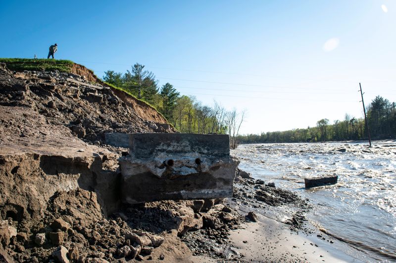 A man on a hill looks at what is left of the Edenville Dam at Wixom Lake on May 21, 2020. The Association of State Dam Safety Officials reviewed Michigan dam safety in September 2020 and found that "Michigan has not invested in the safety of its dams for many decades."