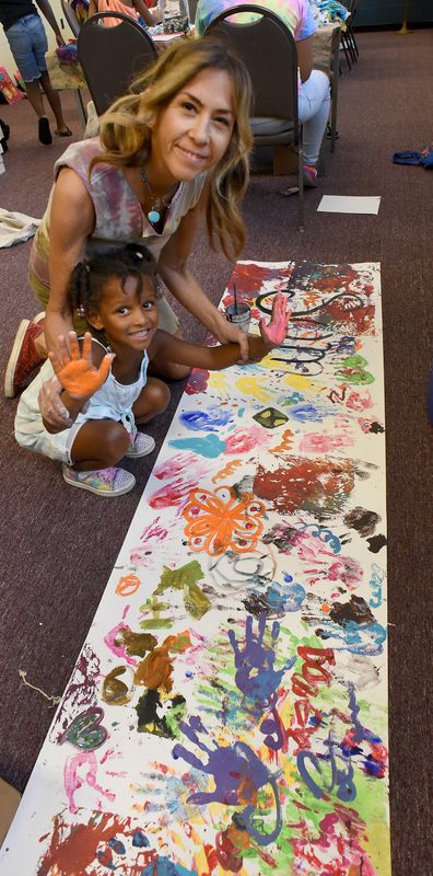Local artist Amy Arnold helps camper Zariah Madison, then 4, place her painted hands onto a banner. The project was part of a previous session of Art with Amy, offered by the Opportunity Center at the Arthur Lesow Community Center in Monroe. The center is offering weekly camps, including Art with Amy, again this summer.