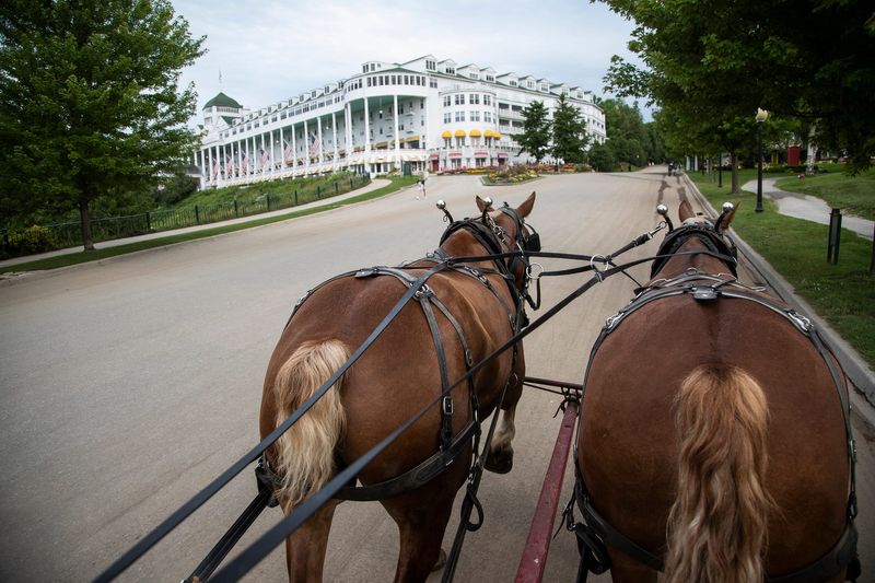 Horses Cooper and Foster pull the horse waste wagon uphill on Cadotte Avenue on Mackinac Island on July 22, 2021.