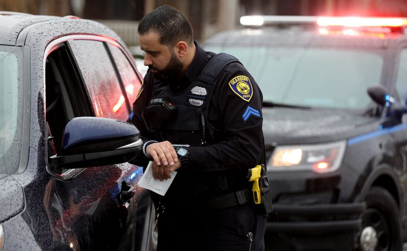 Corporal Mohamad Farhat of the Dearborn Police Department with traffic enforcement talks with a driver who he pulled over for not coming to a complete stop at a stop sign in a neighborhood in Dearborn on Feb. 11, 2022.