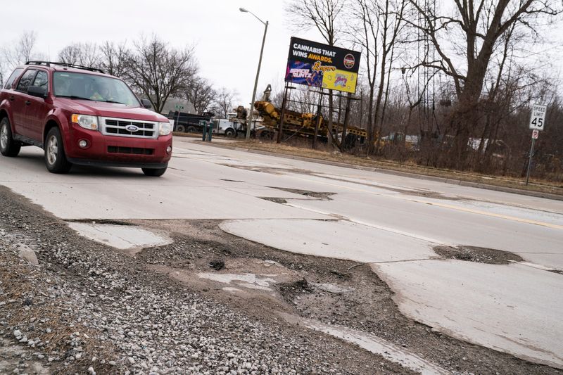 Cars dodge potholes on Eureka Road in Romulus on Feb. 23, 2022.