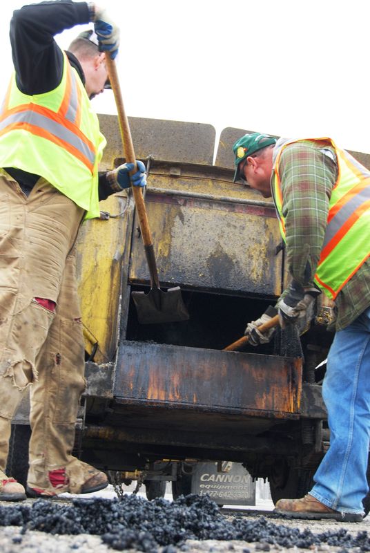 Greg Gooch, left, and Bill Muggelberg of the St. Clair County Road Commission patch a pothole on Dove Road in Port Huron Township.