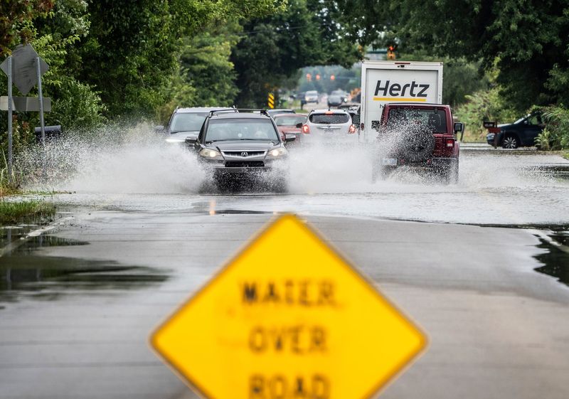 Cars drive through a flooded section of roadway on Geddes Road in Canton on Thursday, August 24, 2023, after heavy rains brought flooding to multiple communities.