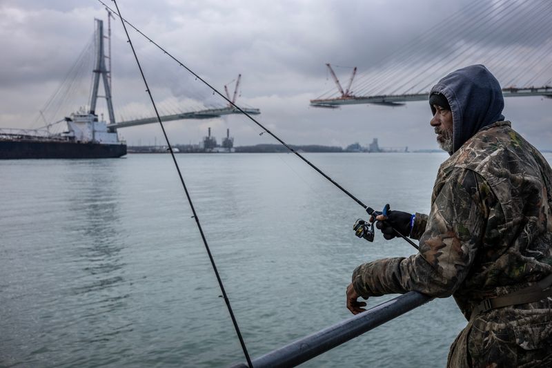 Leonard Kimble of Detroit watches his line in the Detroit River as he fishes for perch and walleye at the Delray Public Access Boat Ramp in Detroit, with the nearly-complete span of the Gordie Howe International Bridge in the background on Thursday, April 4, 2024.