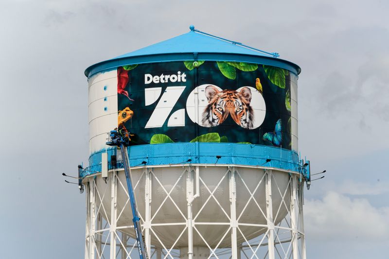 Workers apply a new design to the water tower at the Detroit Zoo, in Royal Oak, May 28, 2024.
