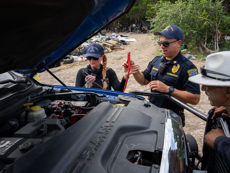 Austin-Travis County EMS Community Health Captain Amber Price, left, and Commander Tim Fuentes use a command truck to jump a dead car battery while visiting an encampment near Ben White Boulevard and Riverside Drive in Austin July 11, 2024. In her role as Community Health Captain, Price focuses on building relationships with Austin's unhoused community to connect them with resources that keep them from needing emergency medical intervention, saving them from a hospital visit and helping to conserve EMS resources.