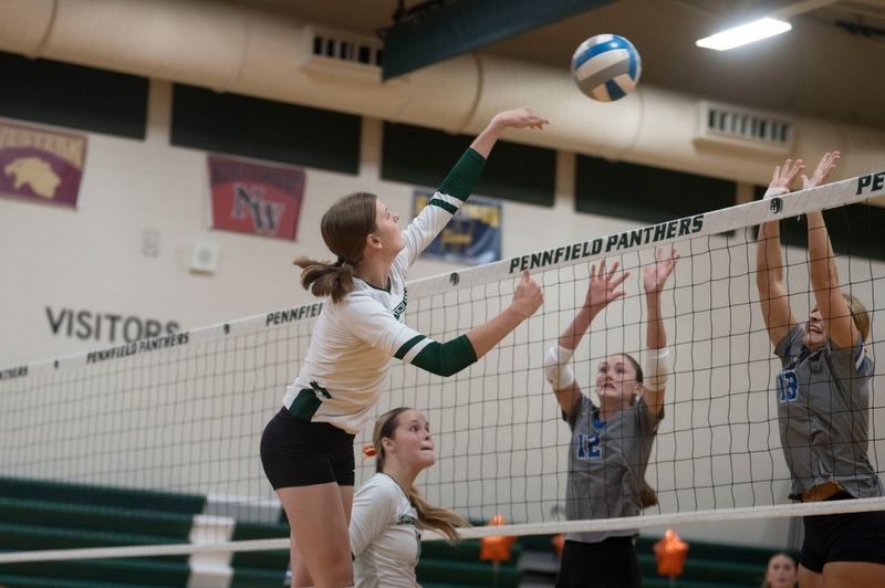 Pennfield senior Natalie Hensel spikes while Harper Creek seniors Cassidy Pratley and Ella Chantrenne attempt to block during a fundraiser game at Pennfield High School on Wednesday, Sept. 18, 2024.