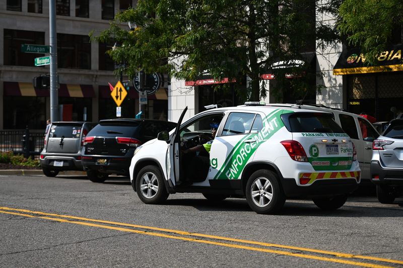 A Lansing parking enforcement officer prepares to ticket a car in downtown Lansing Thursday, Sept. 12, 2024.