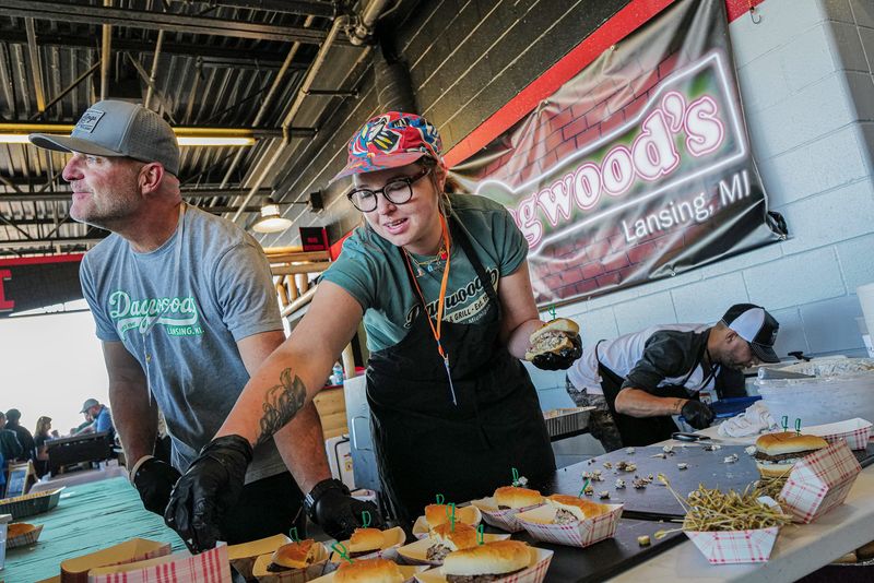 Randy Farlin, left and Darci Donbrock from Dagwood's, work quickly to serve the line of customers waiting to try their olive burgers at the second annual Olive Burger Festival at Jackson Field Saturday, Oct. 5, 2024.