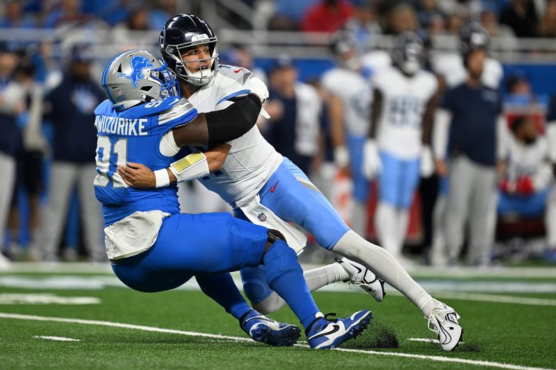 Tennessee Titans quarterback Mason Rudolph (11) gets pulled to the ground by Detroit Lions defensive end Levi Onwuzurike (91) after throwing an interception in the first quarter at Ford Field on Sunday, Oct. 27, 2024 in Detroit.