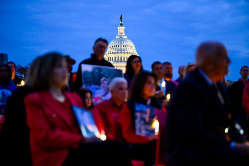 People hold images of victims of drunken driving and listen to speakers’ remarks as the U.S. Capitol looms in the background during a candlelight vigil organized by Mothers Against Drunk Driving (MADD) on the National Mall on Nov. 19, 2024, in Washington, D.C. Advocates for a rule mandating a drunken driving "kill switch" in new vehicles face a virulent opposition campaign online and from some members of Congress.
