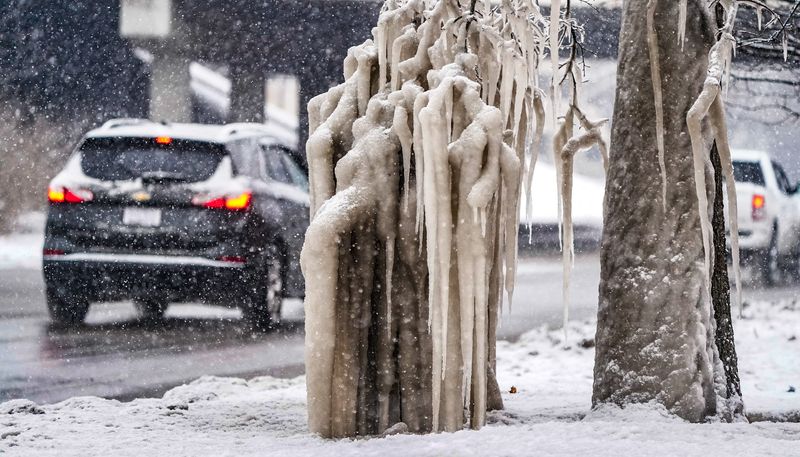 A natural ocuring ice tree gathers exhaust fumes along W. 16th St. near Michigan Rd., as another wave of heavy snow passes through downtown on Friday, Jan. 10, 2025 in Indianapolis.