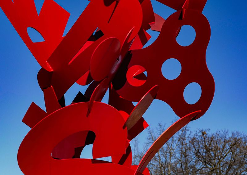 A bright red, steel sculpture stands out in the sunshine and bright blue winter sky in front of East Lansing City Hall Saturday, Jan. 25, 2025.