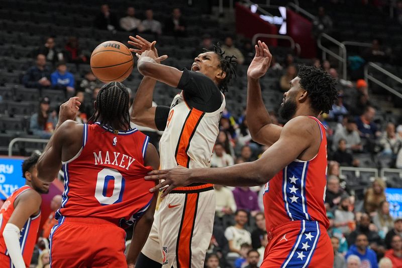 Detroit Pistons forward Ausar Thompson (9) has the ball knocked out of his hands by Philadelphia 76ers center Joel Embiid (21) and Philadelphia 76ers guard Tyrese Maxey (0) during the first half of the game at Little Caesars Arena in Detroit, Friday, Feb. 7, 2025.