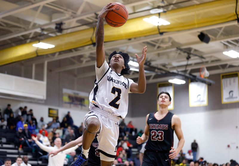 Waverly's De'Shawnta Malone, left, goes up for a layup against Okemos' Christian Chiou (23), Friday, Feb. 14, 2025, at Waverly High School.