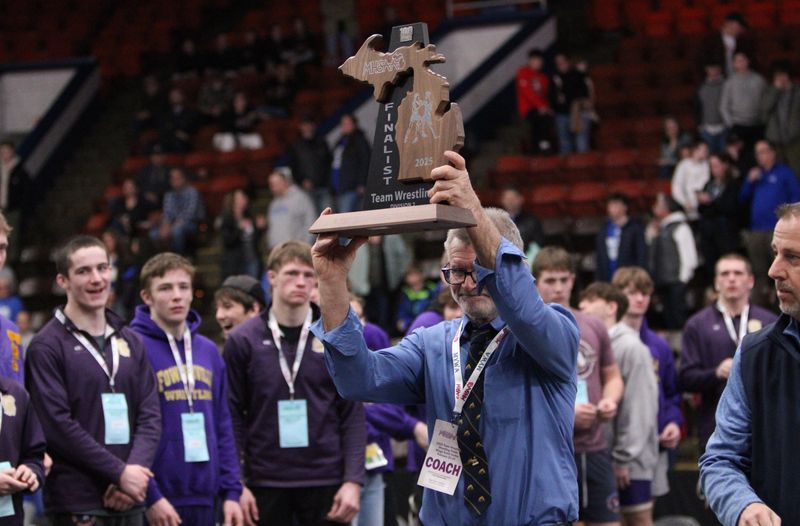Fowlerville wrestling coach Dan Coon hoists the state Division 2 runner-up trophy after a loss to Lowell Saturday, Feb. 22, 2025 at Wings Event Center in Kalamazoo.