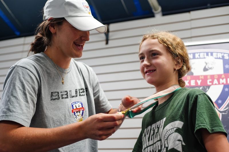 Megan Keller puts her U.S. Gold Olympic medal on Stella Hernandez, 11, of Shelby Township at Megan Keller's Gold Medal Hockey Camp at Suburban Ice in Farmington Hills on Wednesday, July 21, 2021. The camp consisted of fundamental skills, age-appropriate concepts, training on forward and backward skating, playmaking, scoring, puck handling, and defense. There was three age group at the camp.