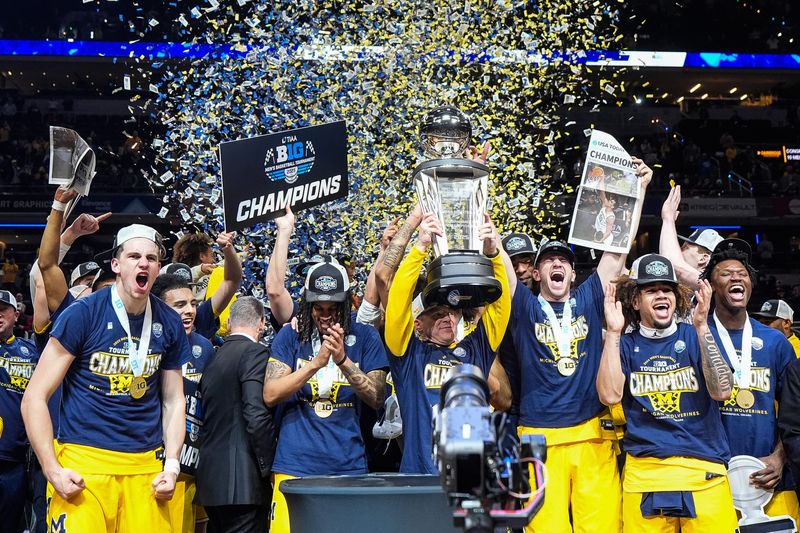 Michigan head coach Dusty May, center right, lifts the trophy to celebrate 59-53 win over Wisconsin with the team at the Big Ten Tournament championship game at Gainbridge Fieldhouse in Indianapolis, Ind. on Sunday, March 16, 2025.