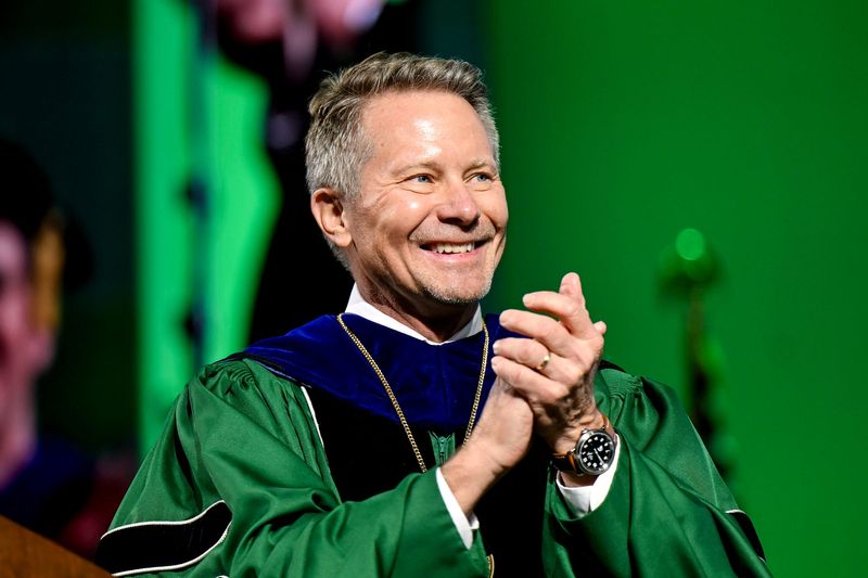President Kevin M. Guskiewicz applauds after a doctoral hood was placed on Mat Ishbia, former MSU basketball players, CEO of United Wholesale Mortgage and owner of the Phoenix Suns, during Michigan State University's spring convocation ceremony on Friday, May 2, 2025, at the Breslin Center in East Lansing. Ishbia was awarded an honorary doctorate in business.