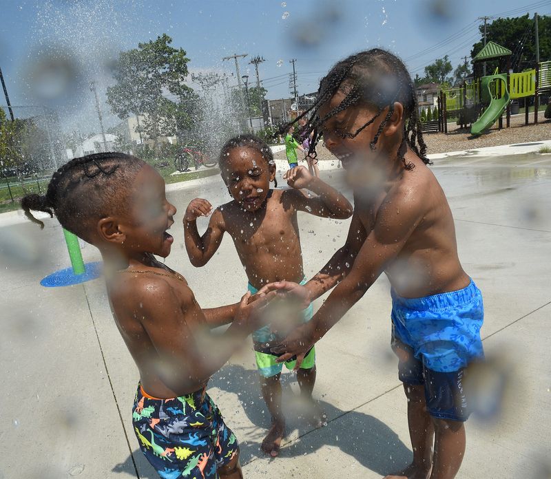 Water drops hitting the lens as Antonio Hester, 4, Carter Adams, 4, and Kayden Hester, 5, enjoy playing at the new City of Monroe Father Cairns Park splash pad Monday, June 17, 2024 as the heat hits many regions.