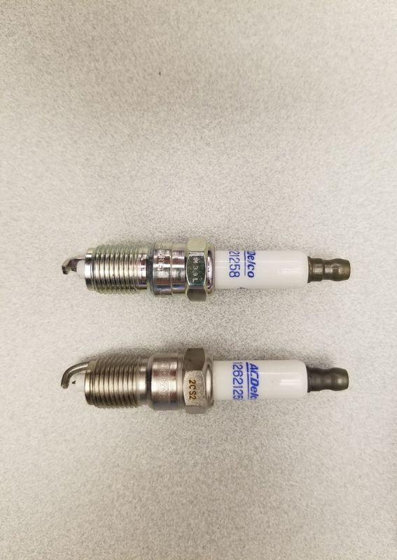 An example showing a counterfeit spark plug, top, and an authentic spark plug, bottom.