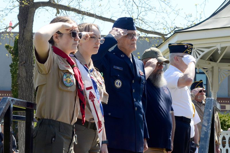 Veterans and scouts salute as Taps is played during the 2025 Memorial Day ceremony in Petoskey's Pennsylvania Park.