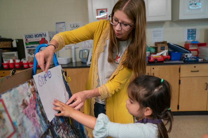 Great Start Readiness Program (GSRP) lead teacher Kirstyn Love helps a student with her artwork at Early Childhood and Kids Club Programs in Whitmore Lake on Friday, May 30, 2025.