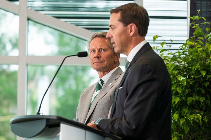 Kevin Guskiewicz's departure for Clemson triggers a clause that cuts the buyout for Michigan State AD J Batt, right, in half.