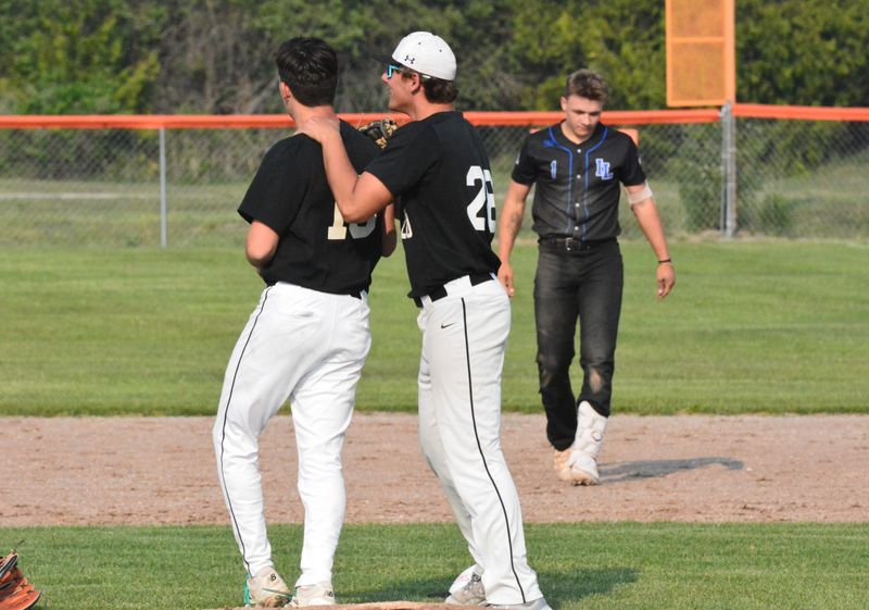 East Jordan's Korbyn Russell and Ryder Malpass celebrate the final out during an MHSAA Division 4 baseball regional semifinal against Inland Lakes in Rogers City on Wednesday. Inland Lakes senior Aidan Fenstermaker (right) hammered a ball deep into the outfield, but it was caught by East Jordan's Max Beal.