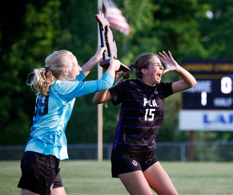 Plymouth Christian Academy's Clare Binder, right, and Mary Michalak celebrate with their regional championship trophy after defeating Laingsburg 1-0, Thursday, June 5, 2025, at Lansing Christian High School.