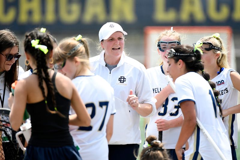 Detroit Country Day lacrosse head coach Liz Nussbaum, center, gives instructions to her team during overtime.