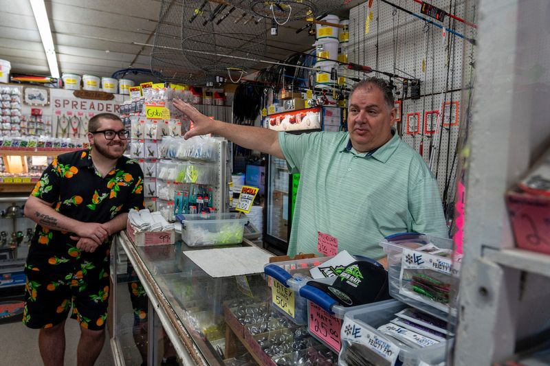 Brian Mogielski, 24, left, smiles as he listens to his father speak, Jim Mogielski, 55, owner of Moe’s Bait Shop, inside the store in Detroit on Wednesday, June 11, 2025. The shop, founded by Jim’s late father in 1966, has become a longtime destination for local anglers and families, especially around Father’s Day.