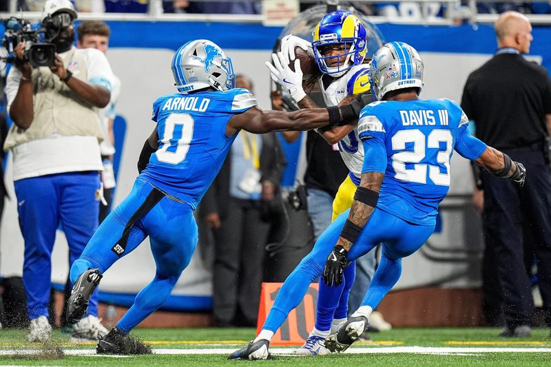 Detroit Lions cornerback Terrion Arnold (0) and cornerback Carlton Davis III (23) tackle Los Angeles Rams wide receiver Demarcus Robinson (15) during the second half at Ford Field in Detroit on Sunday, September 8, 2024.