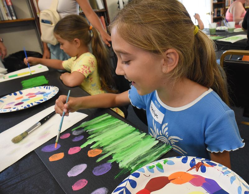 Penelope Patten, 9, working on her canvas acrylic painting of flowers with a variety of colors with her sister Violet, 5, as they took part in the Cookies and Canvas Creations at the Ramsey Memorial Branch Library Wednesday, June 25, 2025 as part of the Color Our World Summer program with the Monroe County Library.