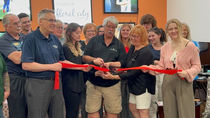 Dave Grassley cuts the ribbon for the grand reopening of Floral City Images.