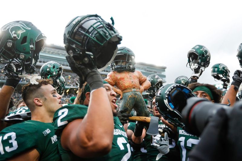 Michigan State players celebrate the 37-33 win over Michigan by raising the Paul Bunyan Trophy at Spartan Stadium in East Lansing on Saturday, Oct. 30, 2021.