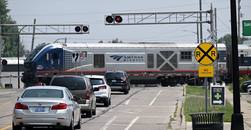 Vehicles stop at the railroad crossing on E. Nine Mile Road near Hilton Road as an Amtrak train rolls by in Ferndale, Mich. on Tuesday, July 15, 2025.