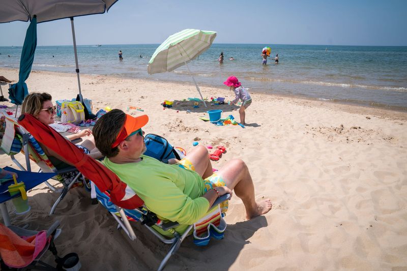 Amy Lawson, left, and her husband, Matthew, watch over their two daughters who are 3 and 7 years old, as they vacation in South Haven from Lebanon, Ohio, on Tuesday, July 15, 2025.