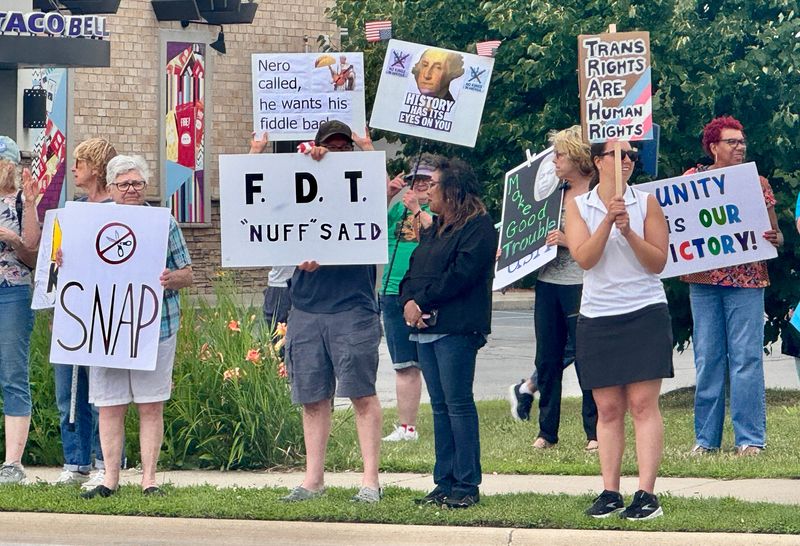 Rallygoers line the sidewalk on 24th Street in Port Huron Township during the Good Trouble Lives On event on July 17, 2025.