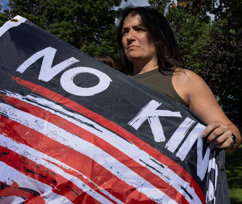 Leanne Reynolds of Holland holds a flag reading “No Kings” during the "Good Trouble Lives On" protest along River Avenue on July 17.