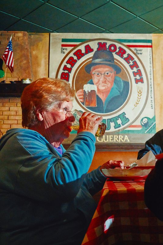 A guest dining alongside a painting of Gus Guerra, the founder of Cloverleaf Pizza.