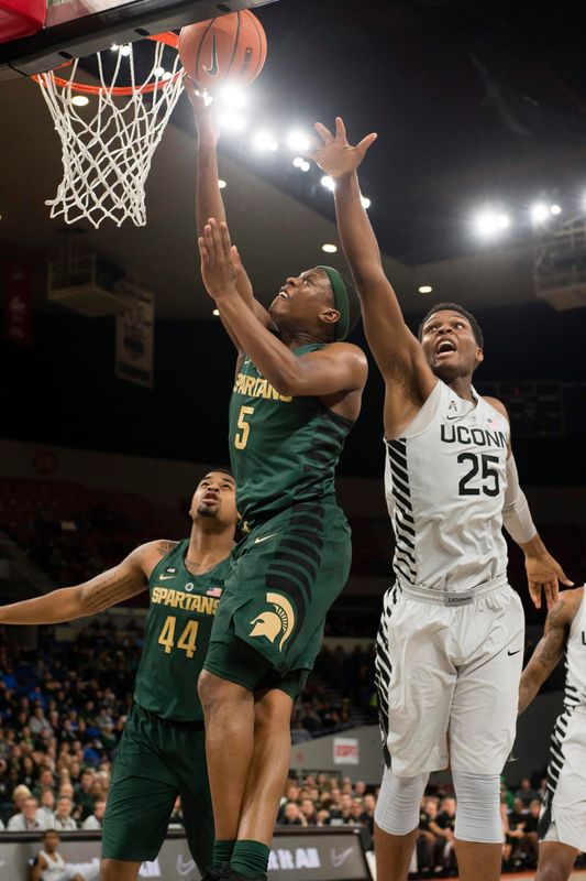 Nov 24, 2017; Portland, OR, USA; Michigan State Spartans guard Cassius Winston (5) scores a basket as he is defended by Connecticut Huskies forward Josh Carlton (25) during the first half during a game at Veterans Memorial Coliseum. Mandatory Credit: Troy Wayrynen-USA TODAY Sports
