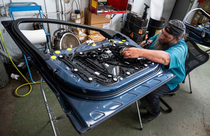 James Duncan, a service technician with Village Ford, works on the front door of a 2020 Ford Escape on Friday, July 25, 2025 at Village Ford in Dearborn. The automaker launched a comprehensive marketing campaign for parts and service on June 1, 2026.