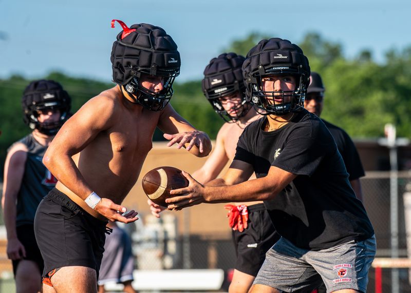 Livonia Churchill's Ali Taleb hands off to Jackson Lauter during a football camp practice on Tuesday, July 29, 2025.