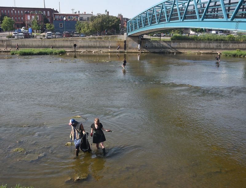 Volunteers Nickica Russell and Ronald Serrano take part in the River Raisin Legacy Project Annual River Raisin Clean Up for the first time on Saturday, August 9, 2025. Above right is the Martin Luther King Jr. Pedestrian Bridge in downtown Monroe.