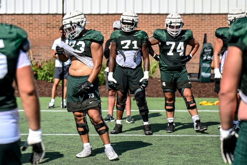 From left, Michigan State's Rustin Young, Kristian Phillips, and Gavin Broscious listen to coaches during football practice on Monday, Aug. 11, 2025, in East Lansing.