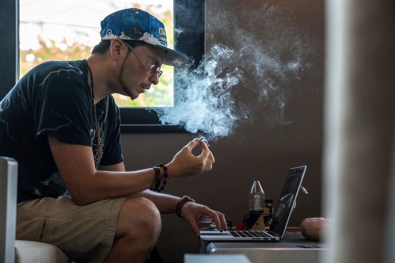 Julian Parra, of Sterling Heights, smokes a pre-rolled joint while editing a video at Macomb County’s first cannabis consumption lounge, Burn1, in Utica on Wednesday, August 13, 2025.